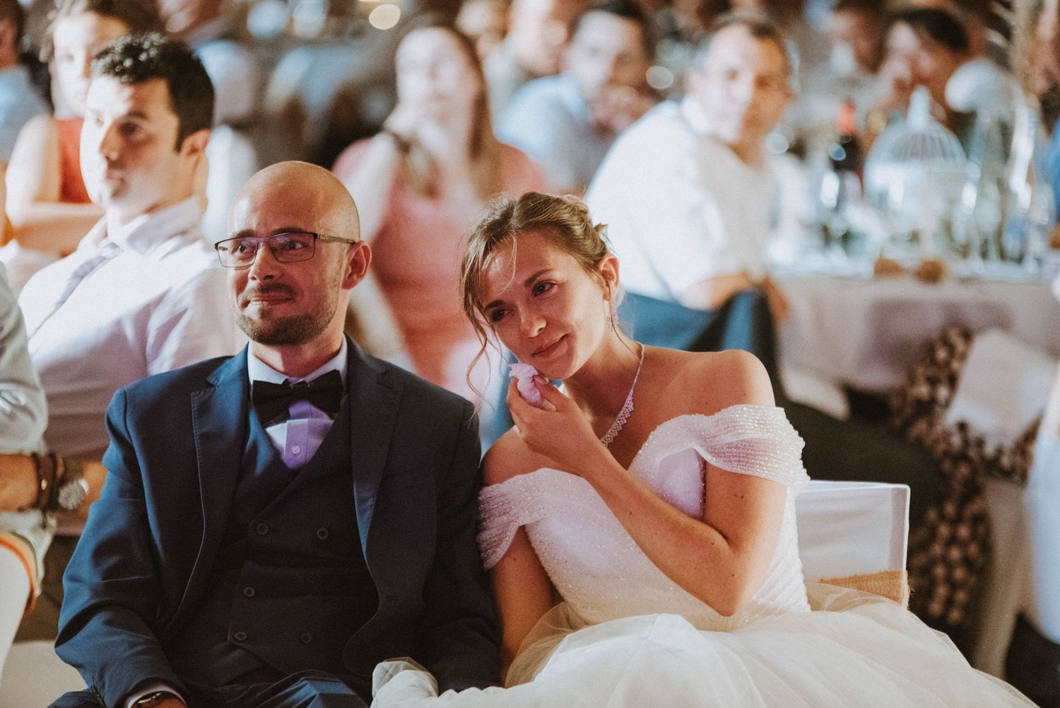 Mariés et invités émus pendant les discours de mariage lors de la réception en Bretagne.