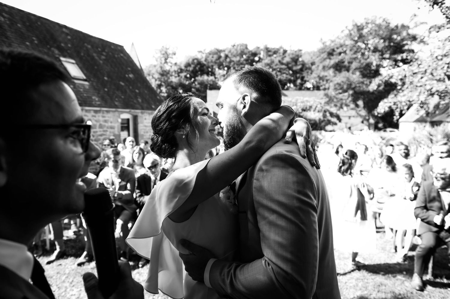 Moment complice en noir et blanc entre invités lors d’un mariage en extérieur en Bretagne.