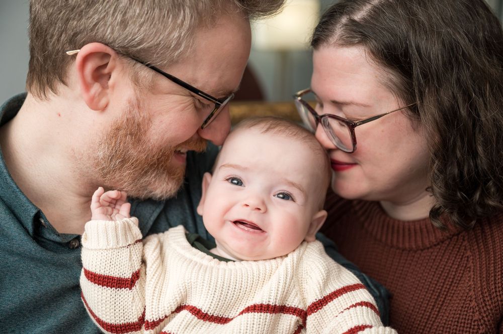A series of tender family moments showing parents sharing loving interactions with their baby in warm lighting.