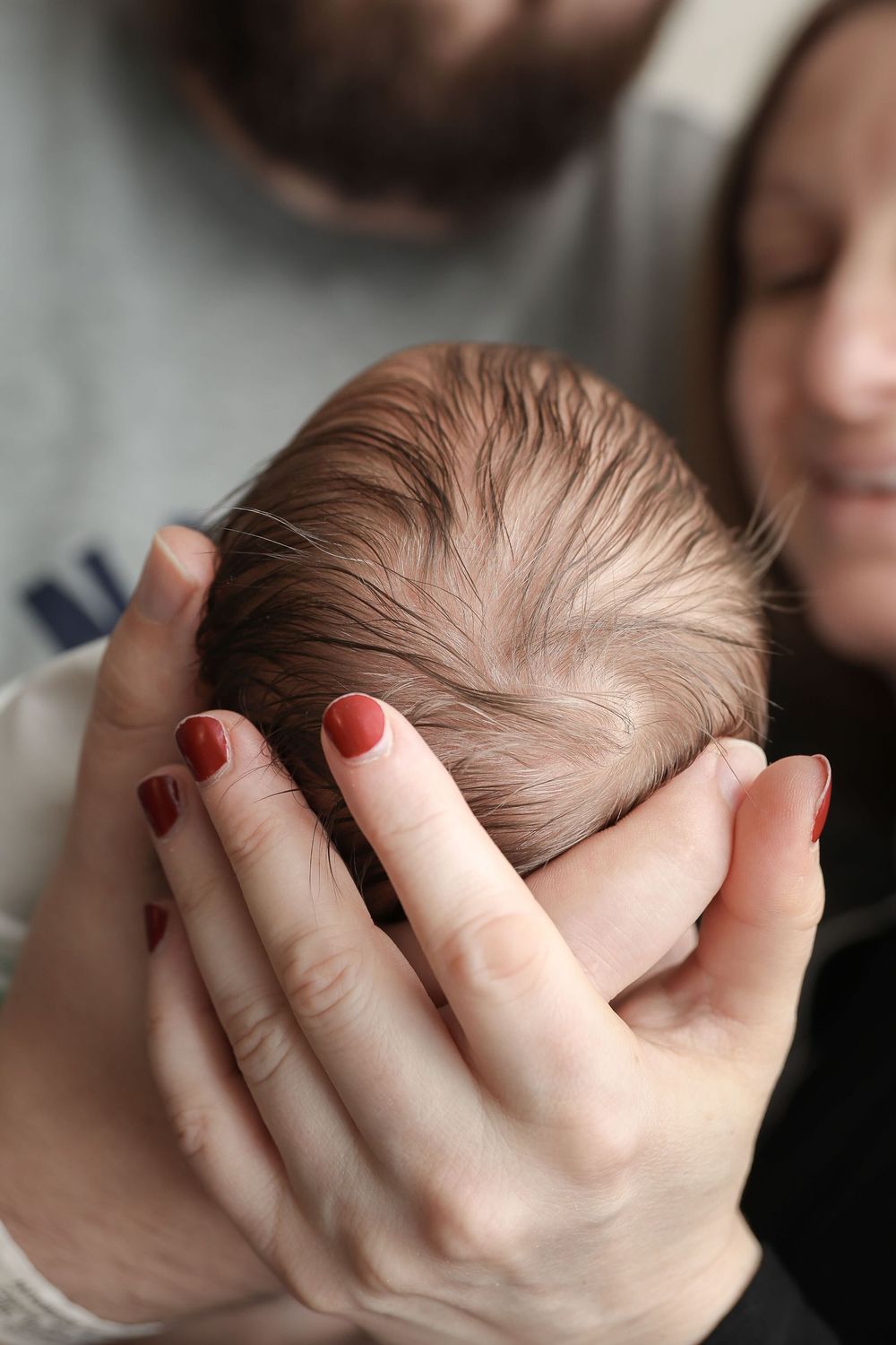 Hands gently cradling and supporting a newborn baby's head in a series of tender poses.