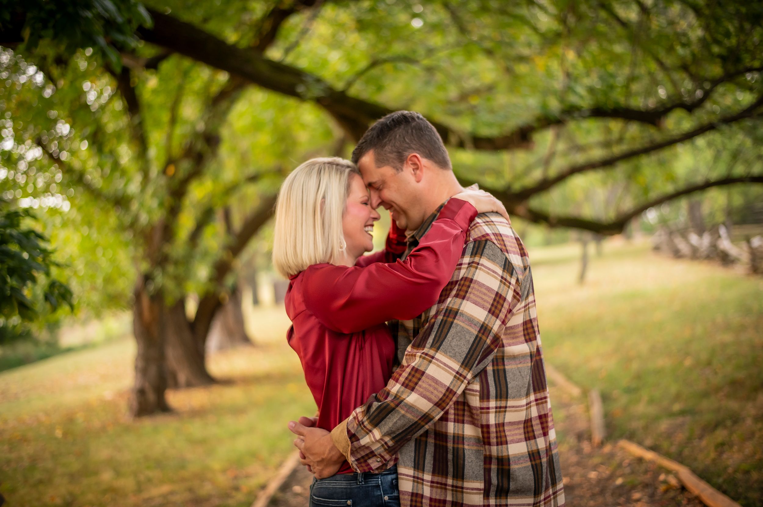 Couple sharing a romantic moment embracing in a tree-lined park during golden hour.