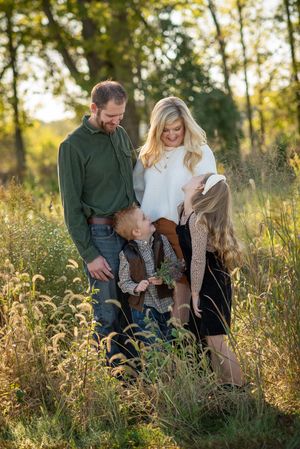 Family of four enjoying a golden hour outdoor photo session in a field of tall grass.