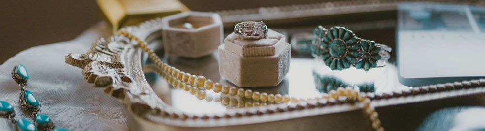 Vintage jewelry and trinkets arranged on a rustic wooden tray with decorative boxes and turquoise beads.