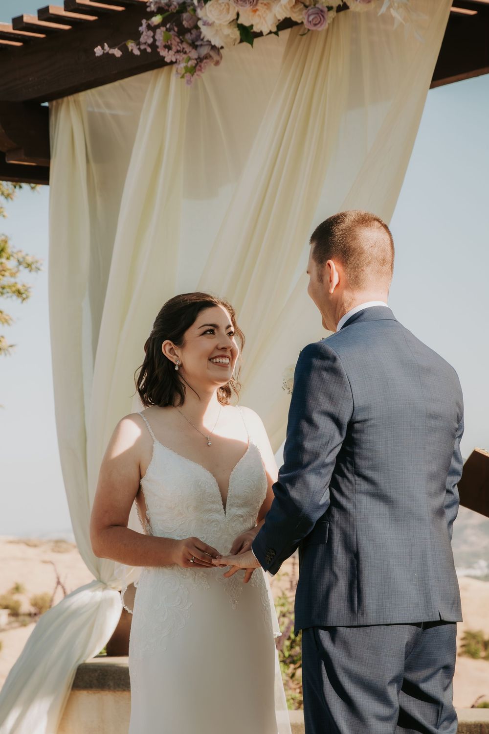 Newlyweds share a joyful moment during their outdoor wedding ceremony under natural lighting.