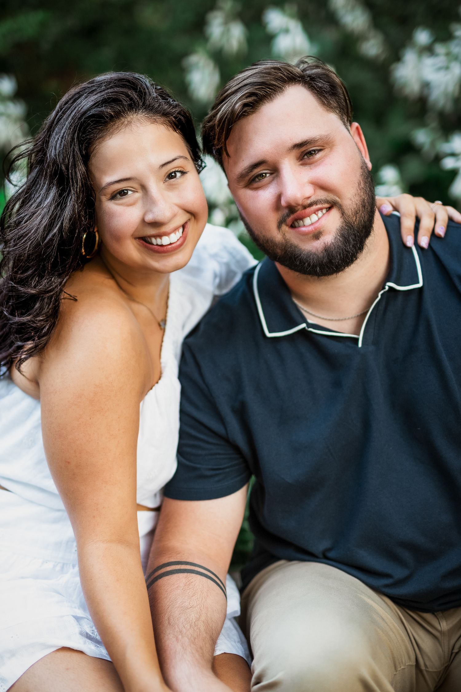 Romantic couple sitting arm-in-arm in the park at golden hour, capturing love and connection with local Windsor photographer, Tasha Cannaday