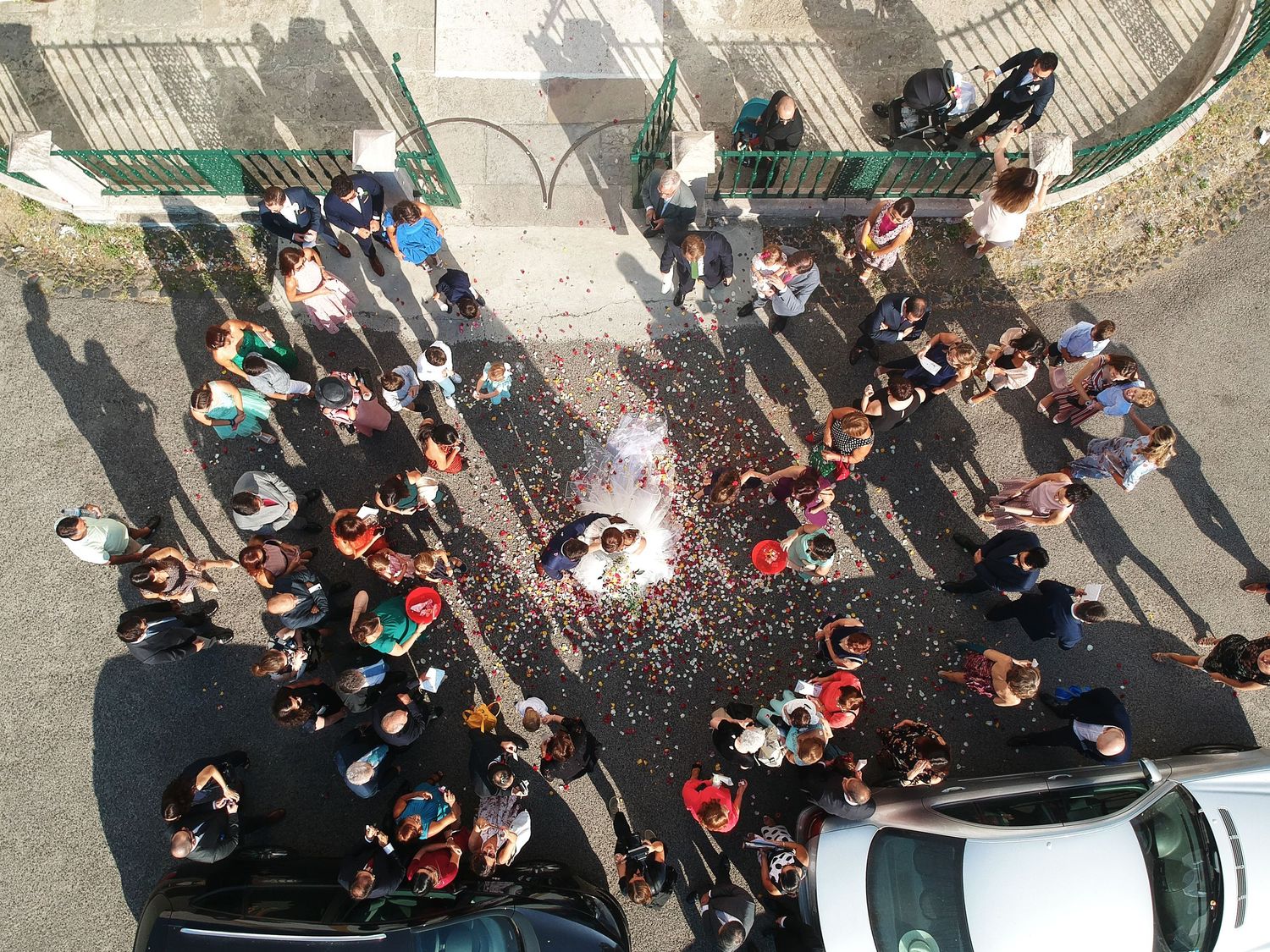 Aerial view of wedding guests throwing confetti during outdoor celebration.