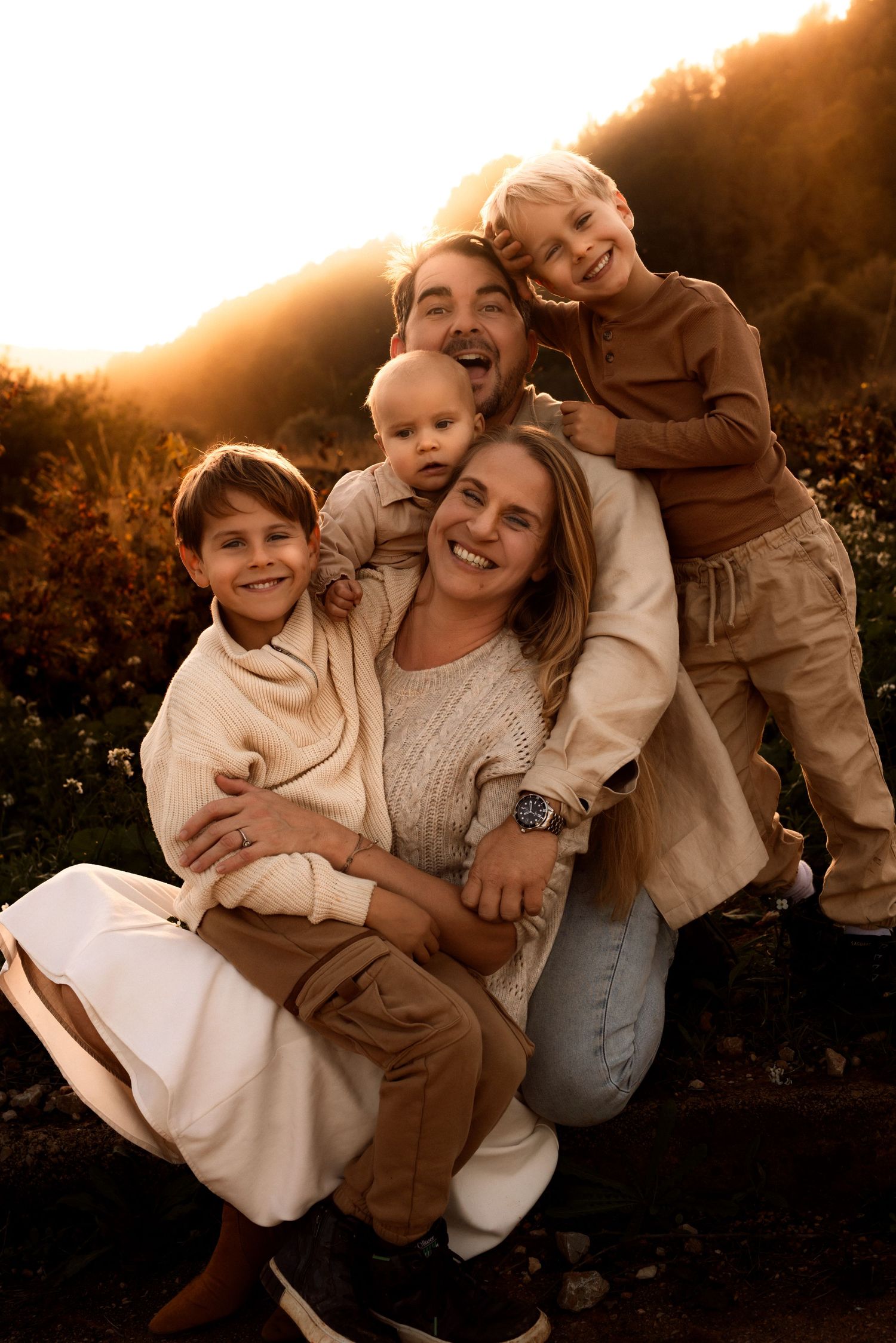 Warm sunset portrait in Denia of family members embracing and smiling together outdoors in golden lighting. Denia photographer