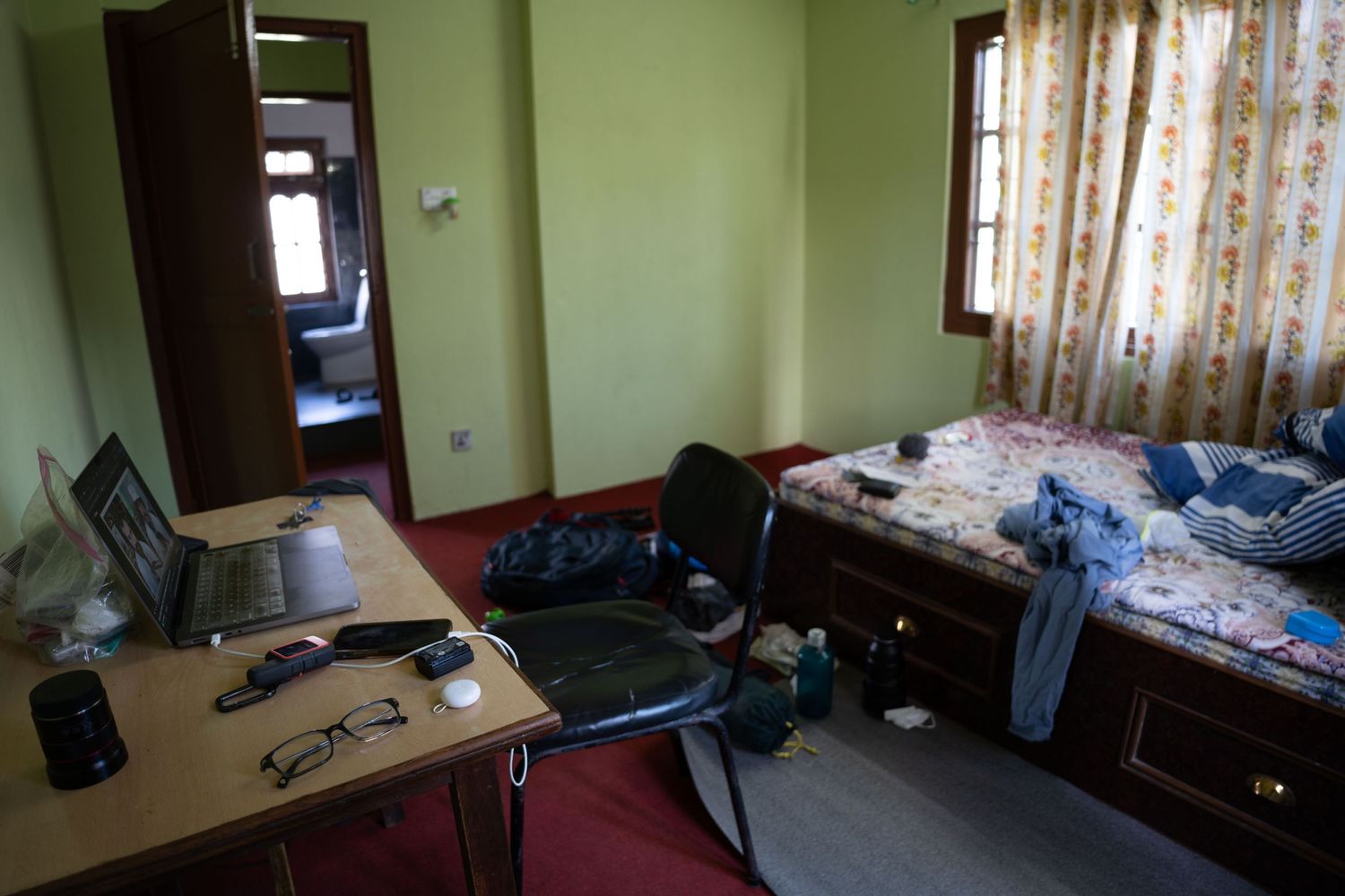 Interior view of a simple hostel room with green walls and basic furnishings.