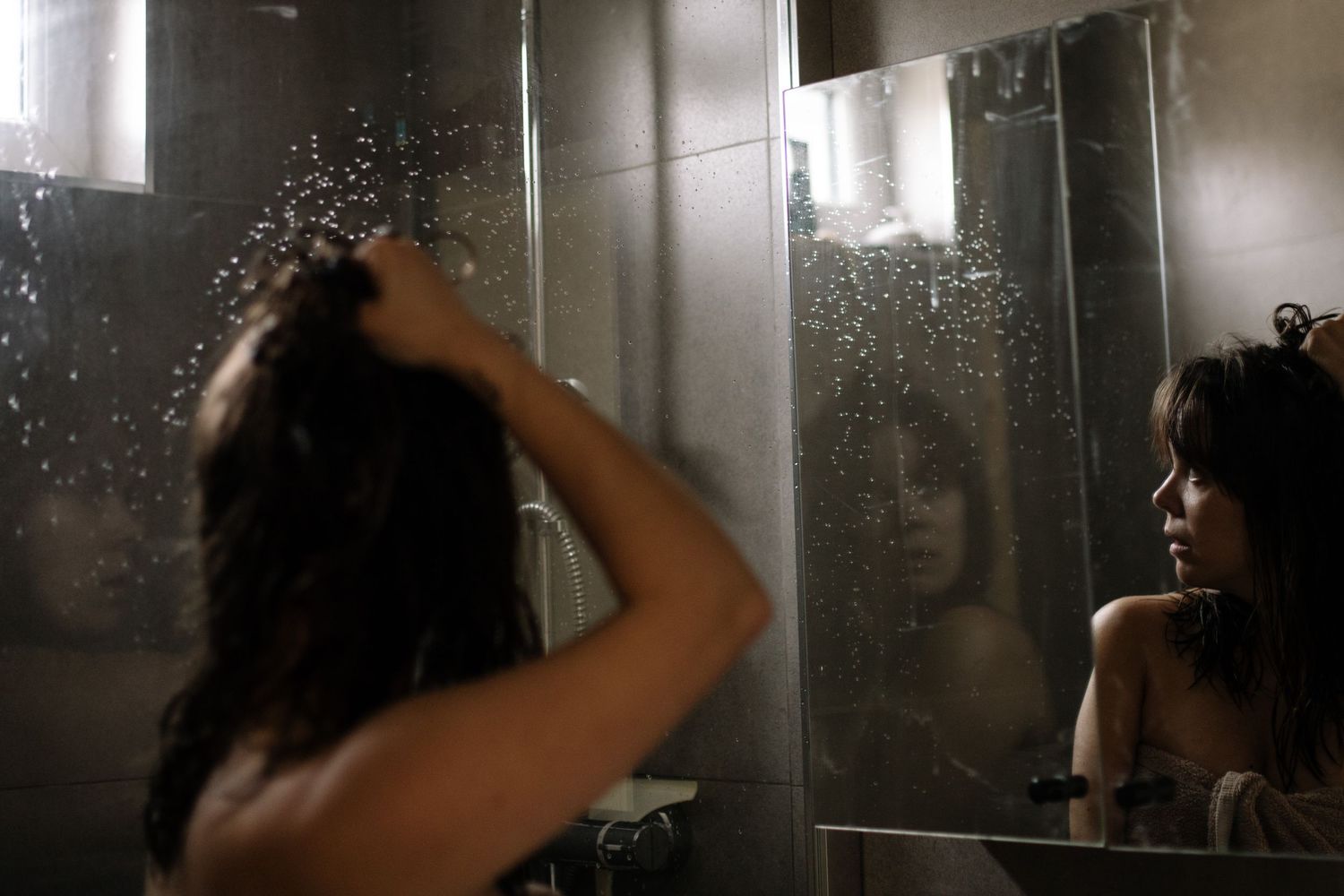 Steam and water droplets on a bathroom mirror create a dreamy reflection effect.