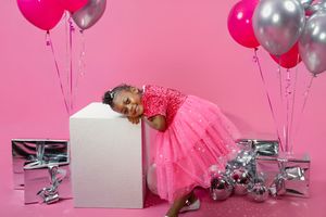 Birthday party setup with pink and silver balloons, disco balls, and festive decorations against a pink backdrop.