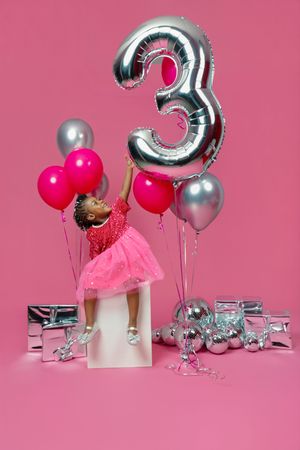 Silver number 3 balloon with pink and metallic decorations against a pink background.
