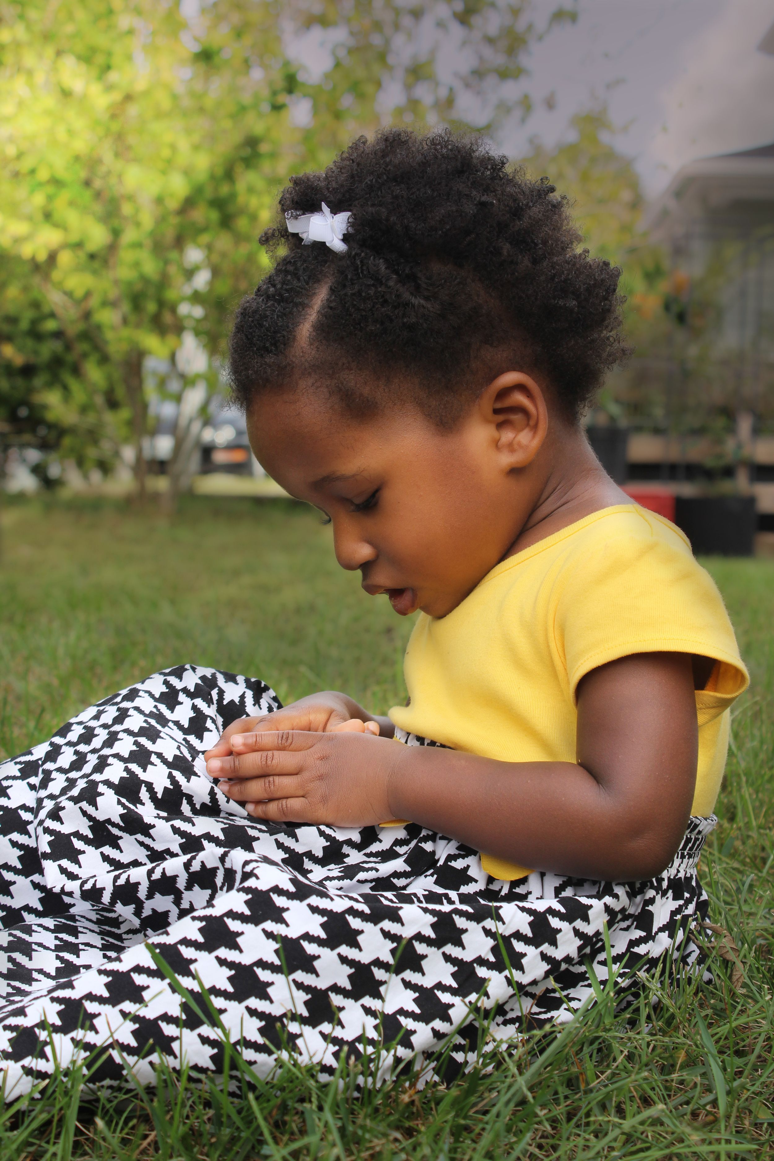 Close-up shot of yellow shirt and houndstooth pattern on grass outdoors.