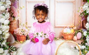 A spring-themed photo setup with pink walls, floral arches, and decorative baskets in a studio setting.