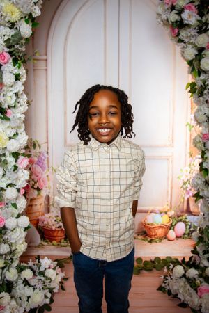 Playful portrait series in a checkered shirt against a floral garden backdrop with white roses.