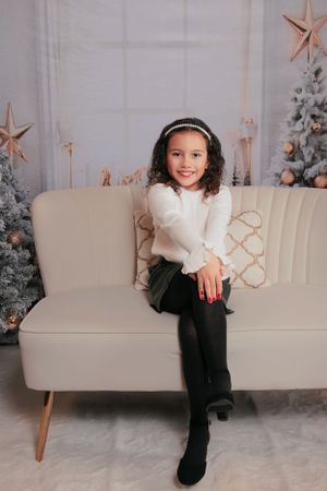 Casual holiday photo session with white sofa and decorated Christmas tree in background.