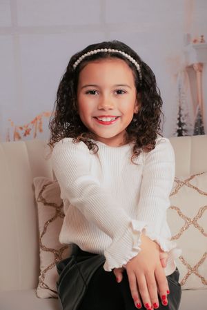 Person in white sweater sitting on beige couch with holiday decor in background.