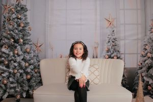 Festive indoor photo setup with cream couch and sparkly star decorations.