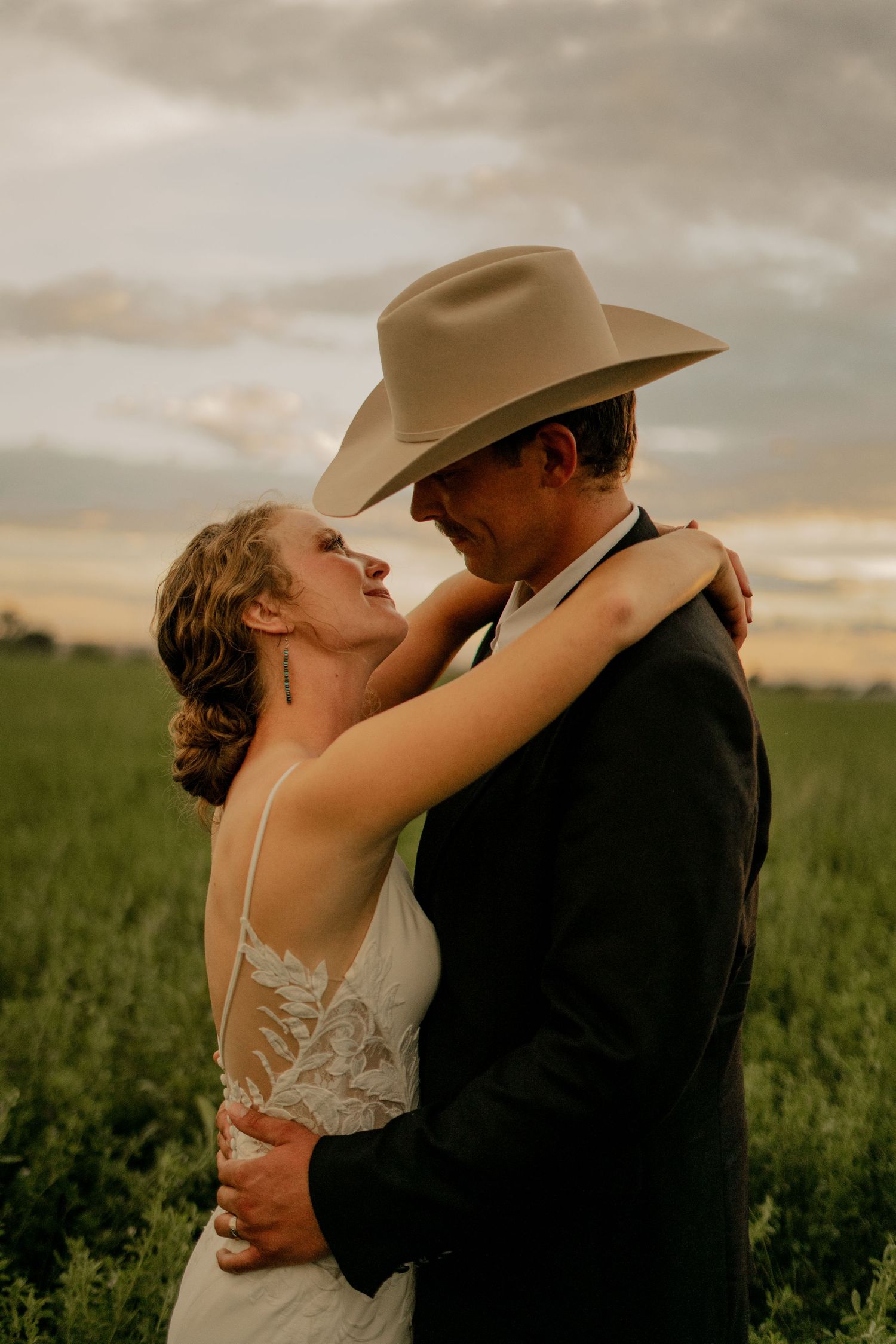 A bride and groom gazing into each others eyes with the sunset in the background