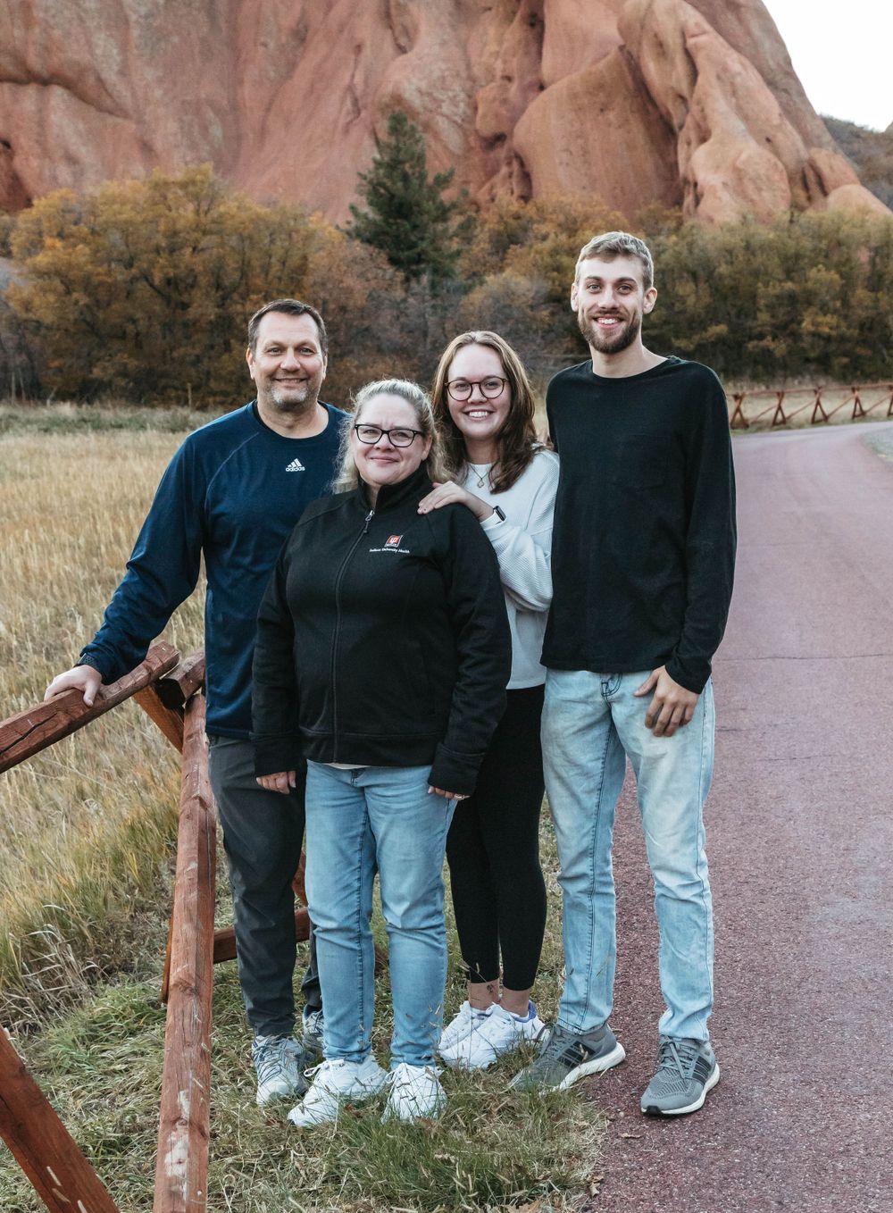 A group of people stand together on a paved path near red rock formations at Garden of the Gods in Colorado.