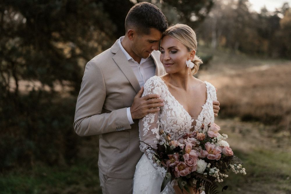 Stimmungsvolles Hochzeitsporträt im Freien mit einem Paar in Beige und Weiß vor einer natürlichen Kulisse.