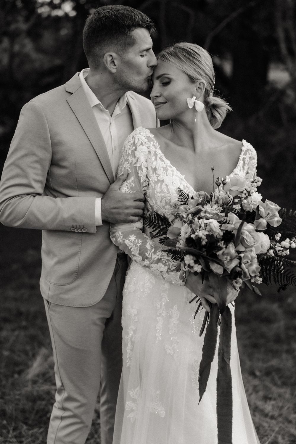 Schwarz-weißes Hochzeitsporträt, das einen intimen Moment mit einem rosa Blumenstrauß zeigt.