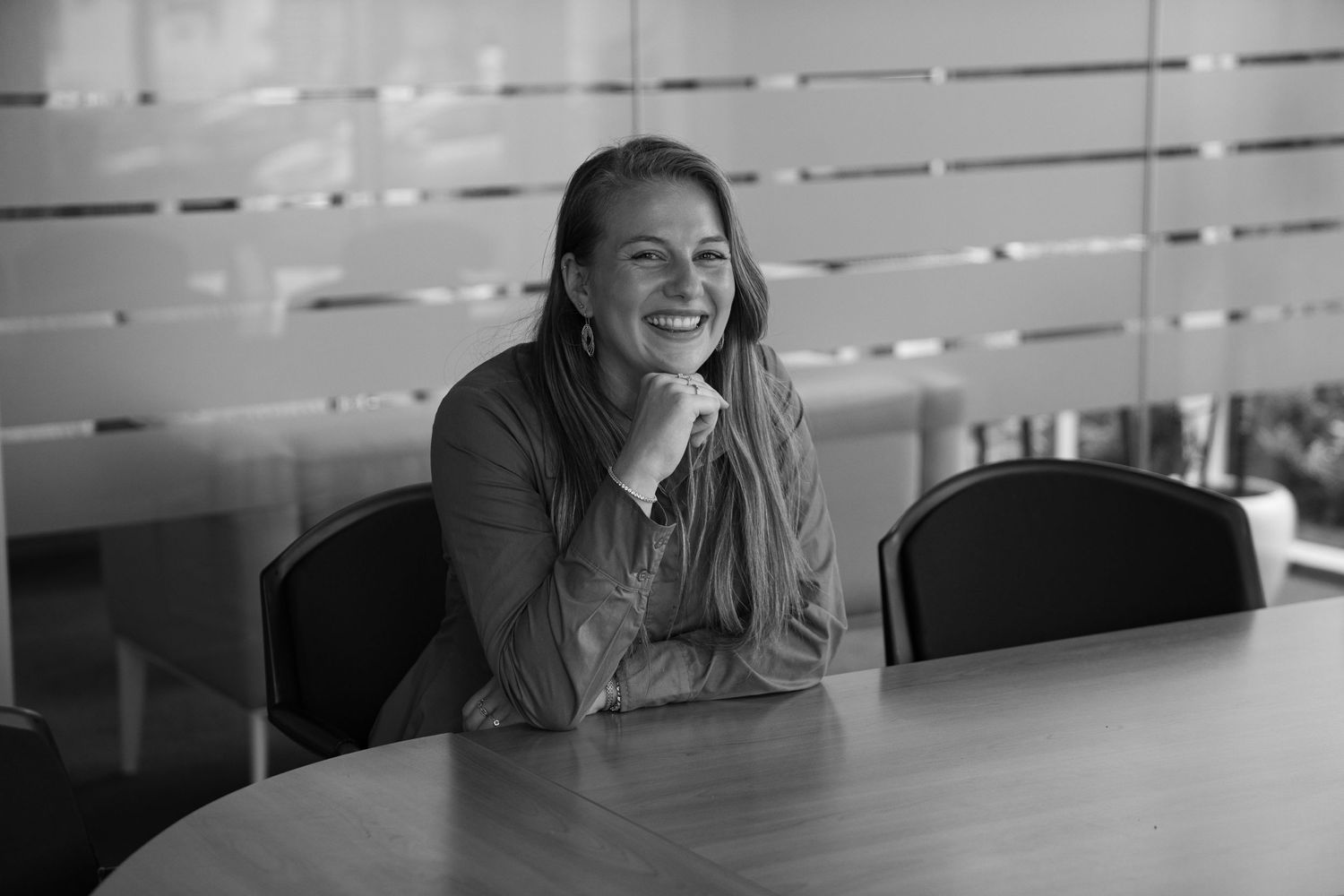 Business portrait of a happy woman sitting at her desk, laughing and engaging in a professional setting in Hasselt.