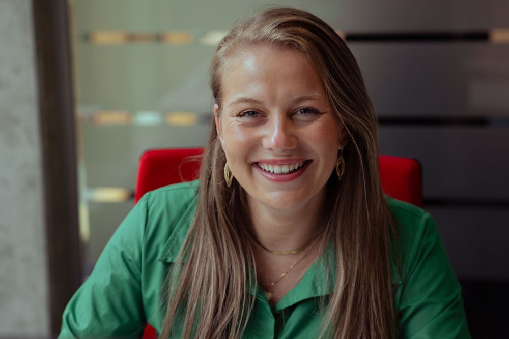 Business portrait of a beautiful woman smiling confidently at the camera, dressed professionally in an office environment in Hasselt.