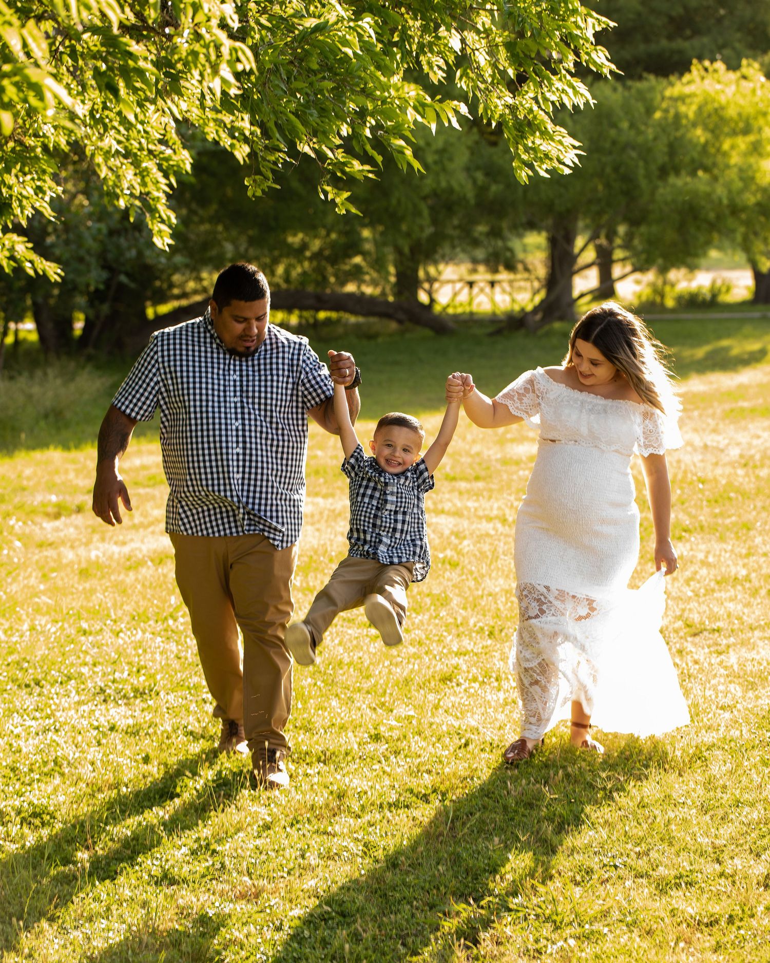 A family enjoys playful moments running together through a sunny grassy field during golden hour.