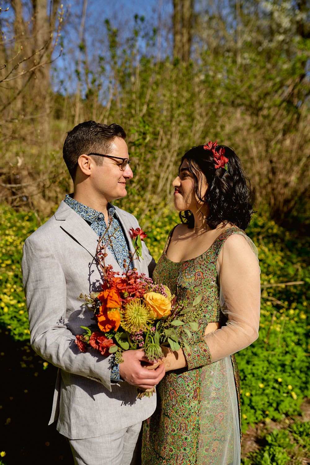 A couple shares a tender moment in a sunny garden while holding a colorful autumn bouquet.
