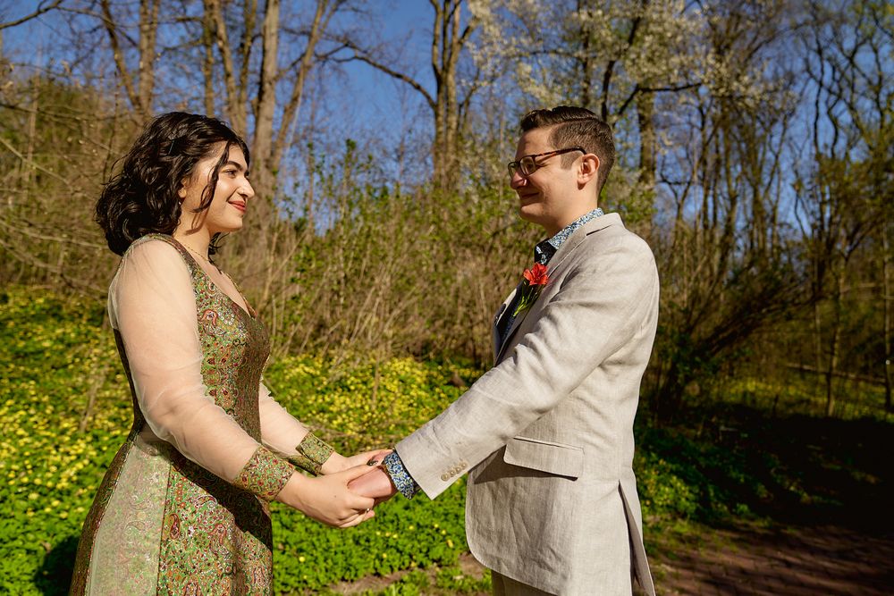 A couple shares a joyful moment in a garden filled with yellow wildflowers on a sunny day.