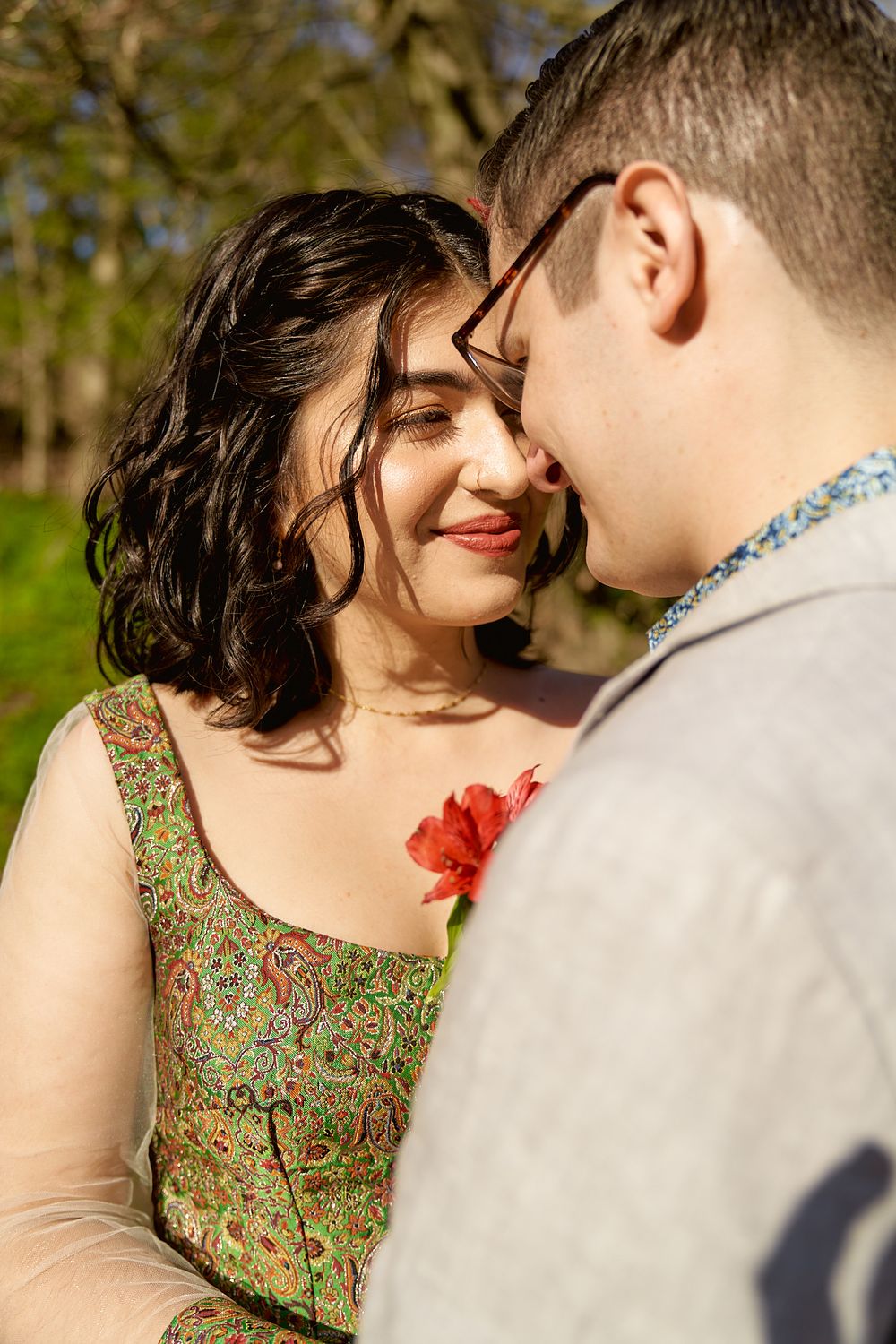 A tender moment captured between a couple in formal wear during an outdoor photoshoot.