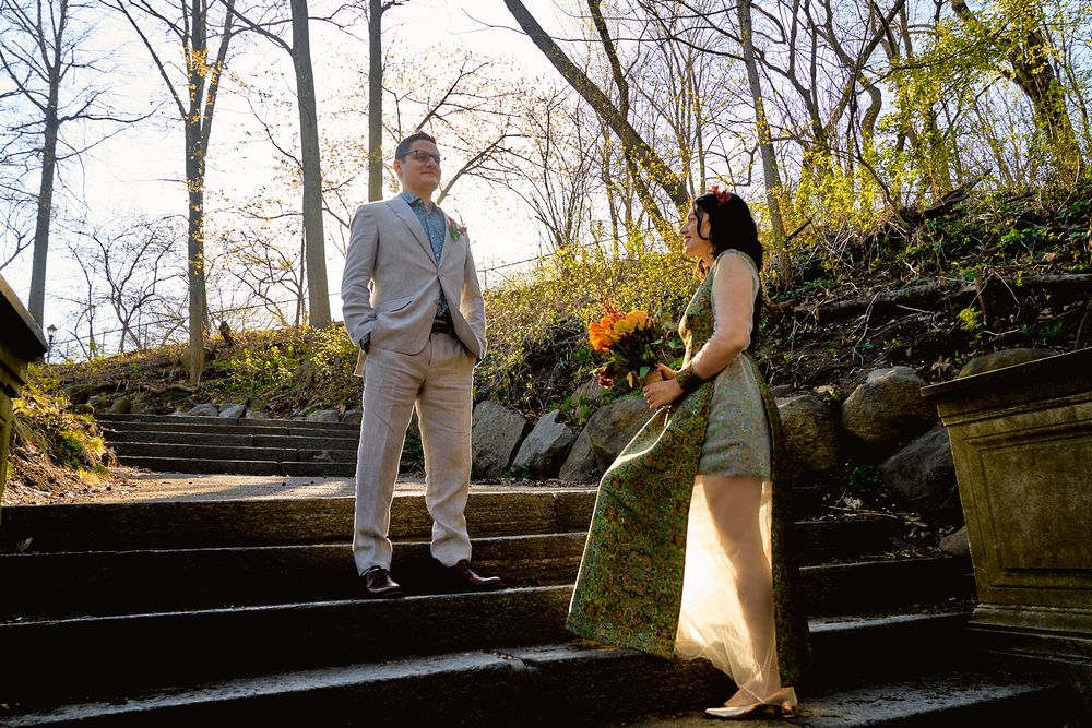 A couple shares a conversation on stone steps in an outdoor garden setting.