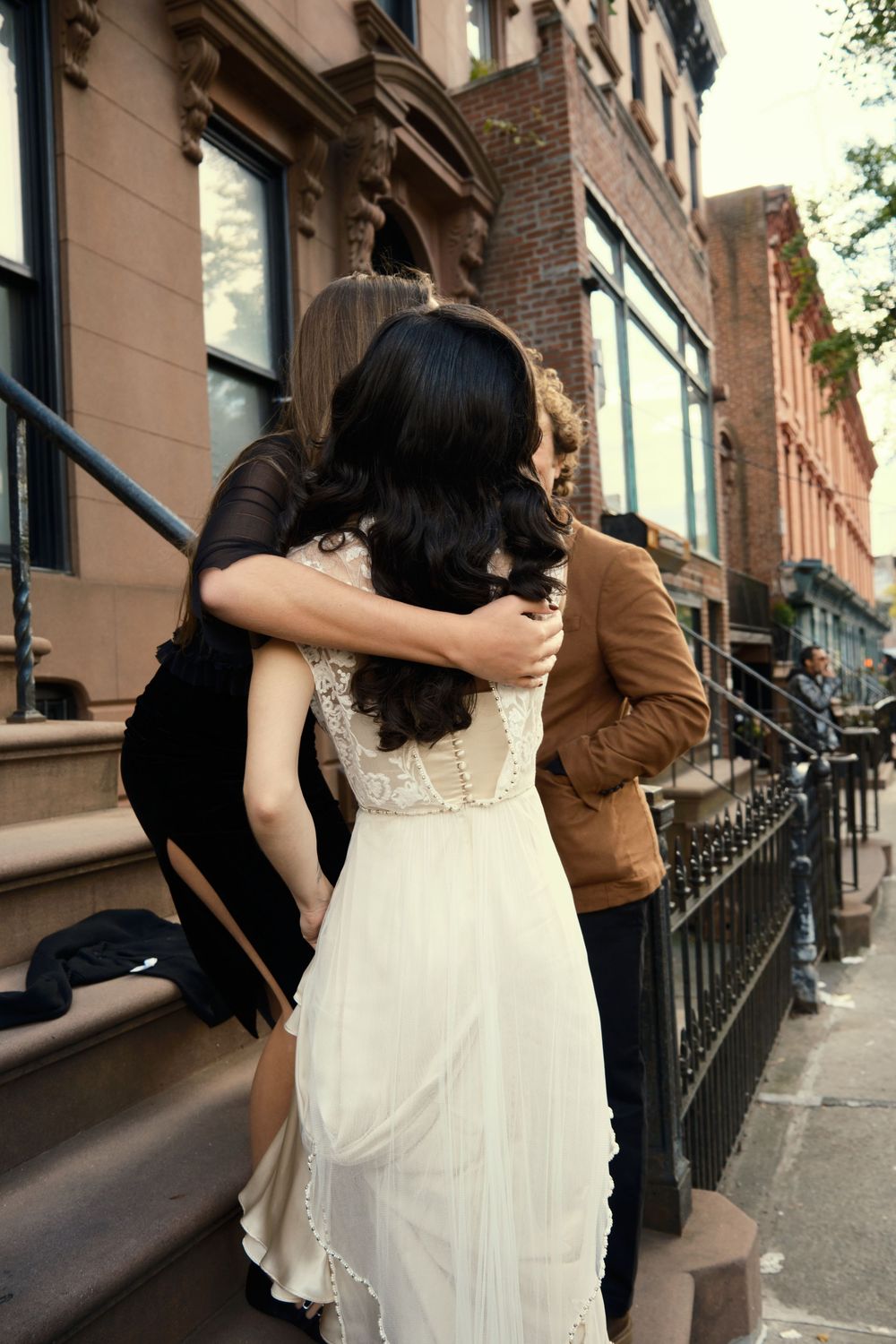 A white wedding dress seen from behind on brownstone steps in an urban setting at Mayson May