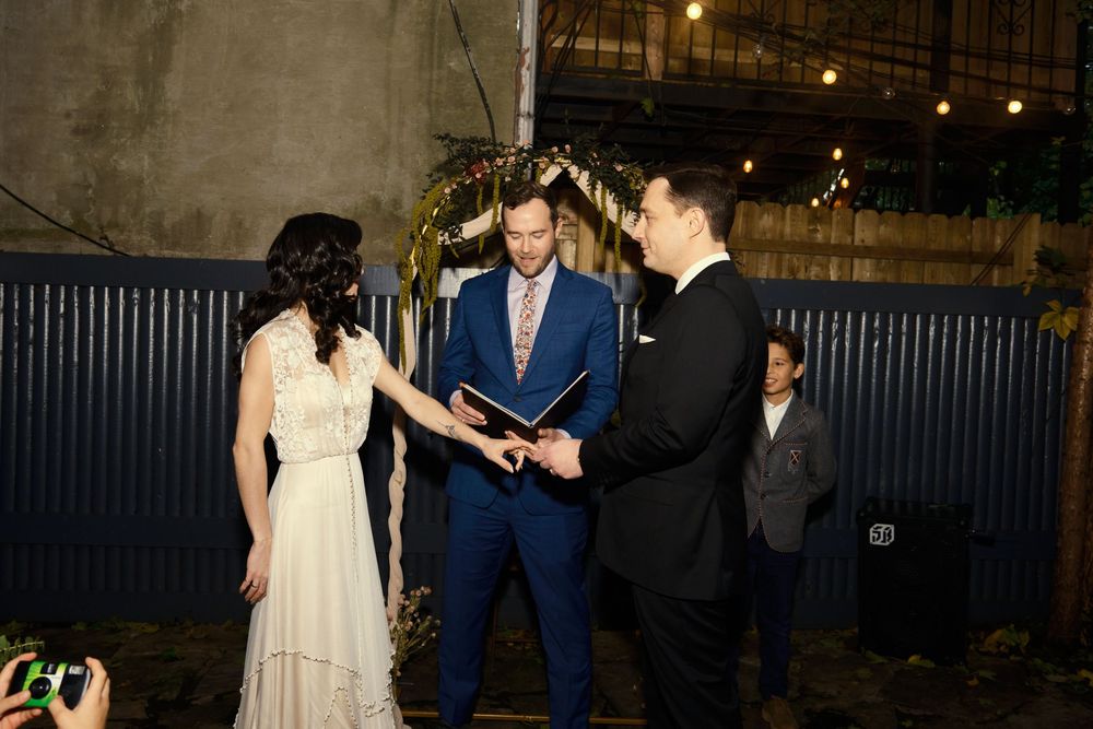 An outdoor wedding ceremony taking place under string lights at dusk at Mayson May