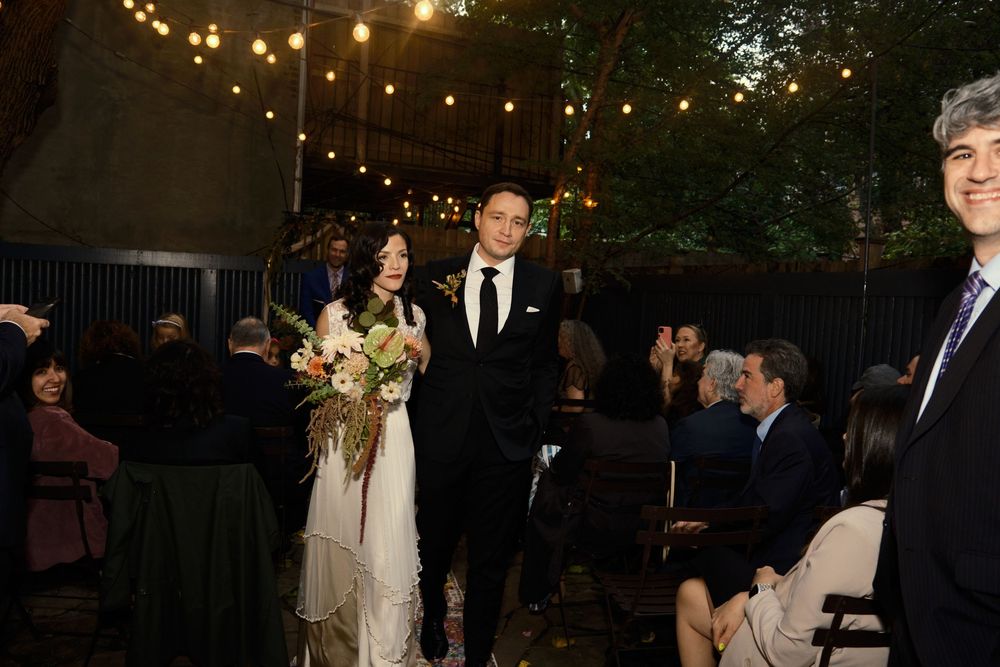 An intimate outdoor evening wedding ceremony under string lights at Mayson May