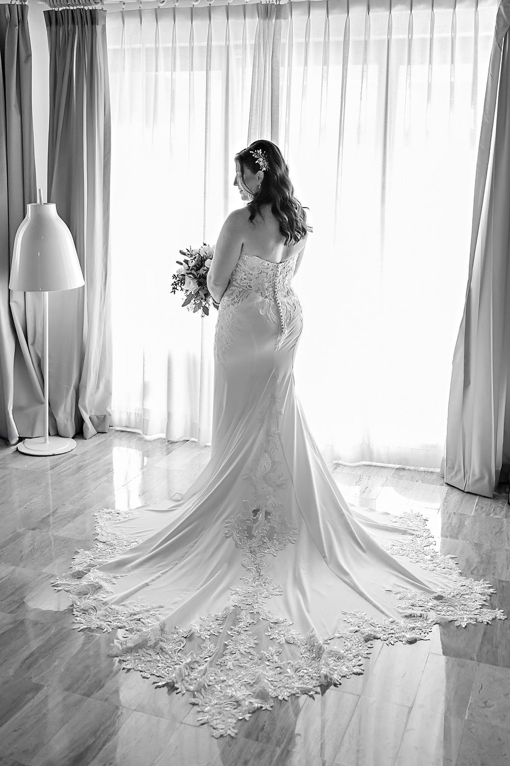 An elegant wedding dress with intricate lace detailing and long train shown in multiple angles in soft window light.
