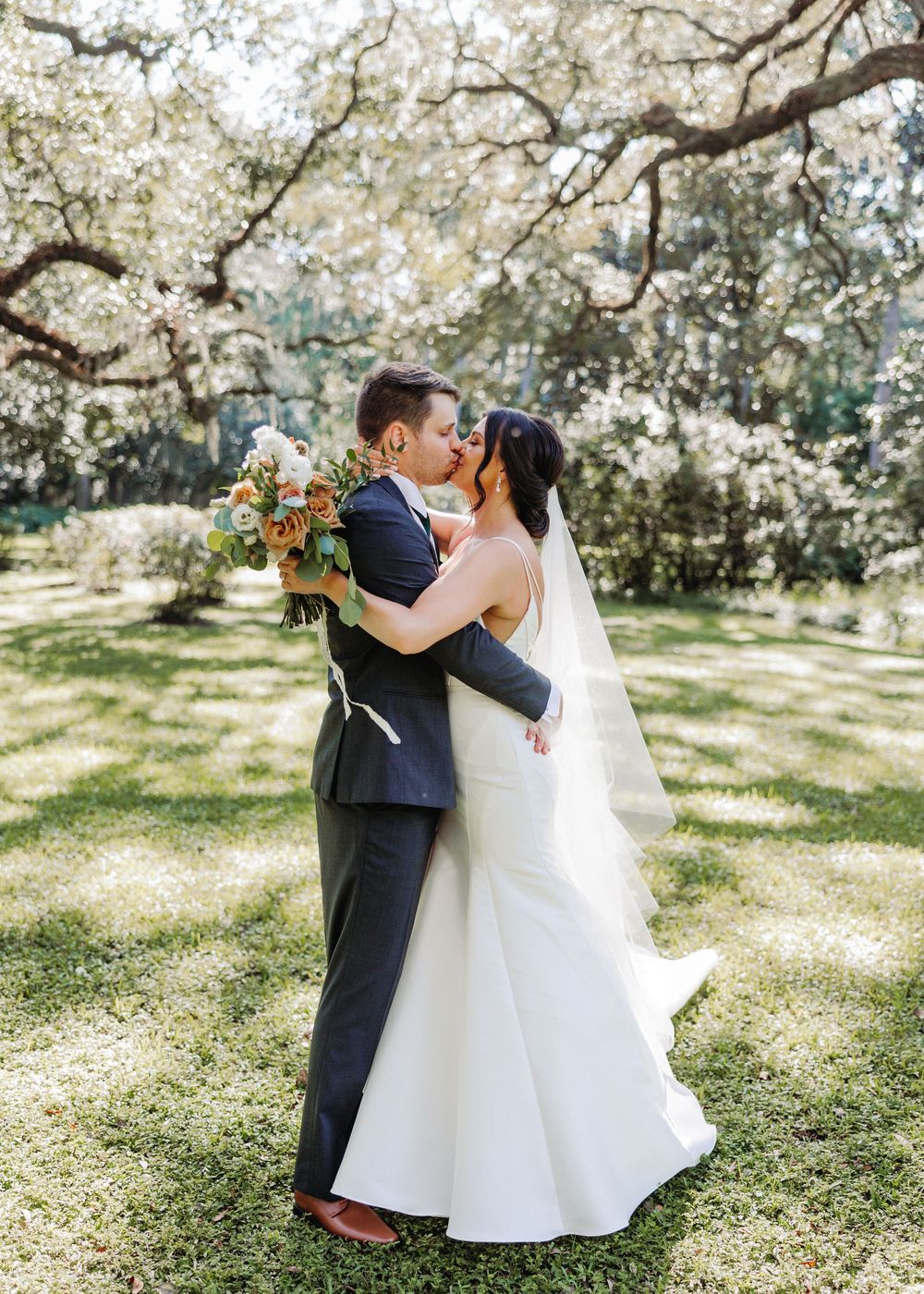 A dreamy wedding photoshoot in a sunlit orchard with blossoming cherry trees creating a romantic springtime atmosphere.