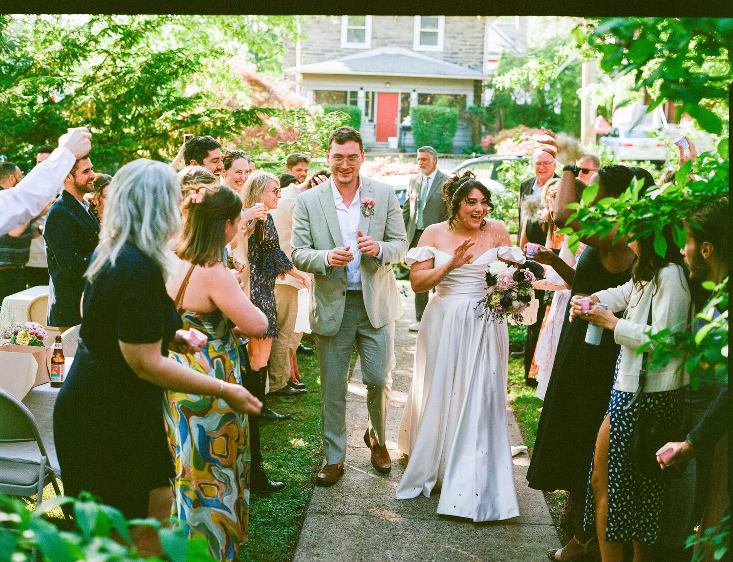 Newlyweds toast with guests during an outdoor afternoon garden wedding reception.