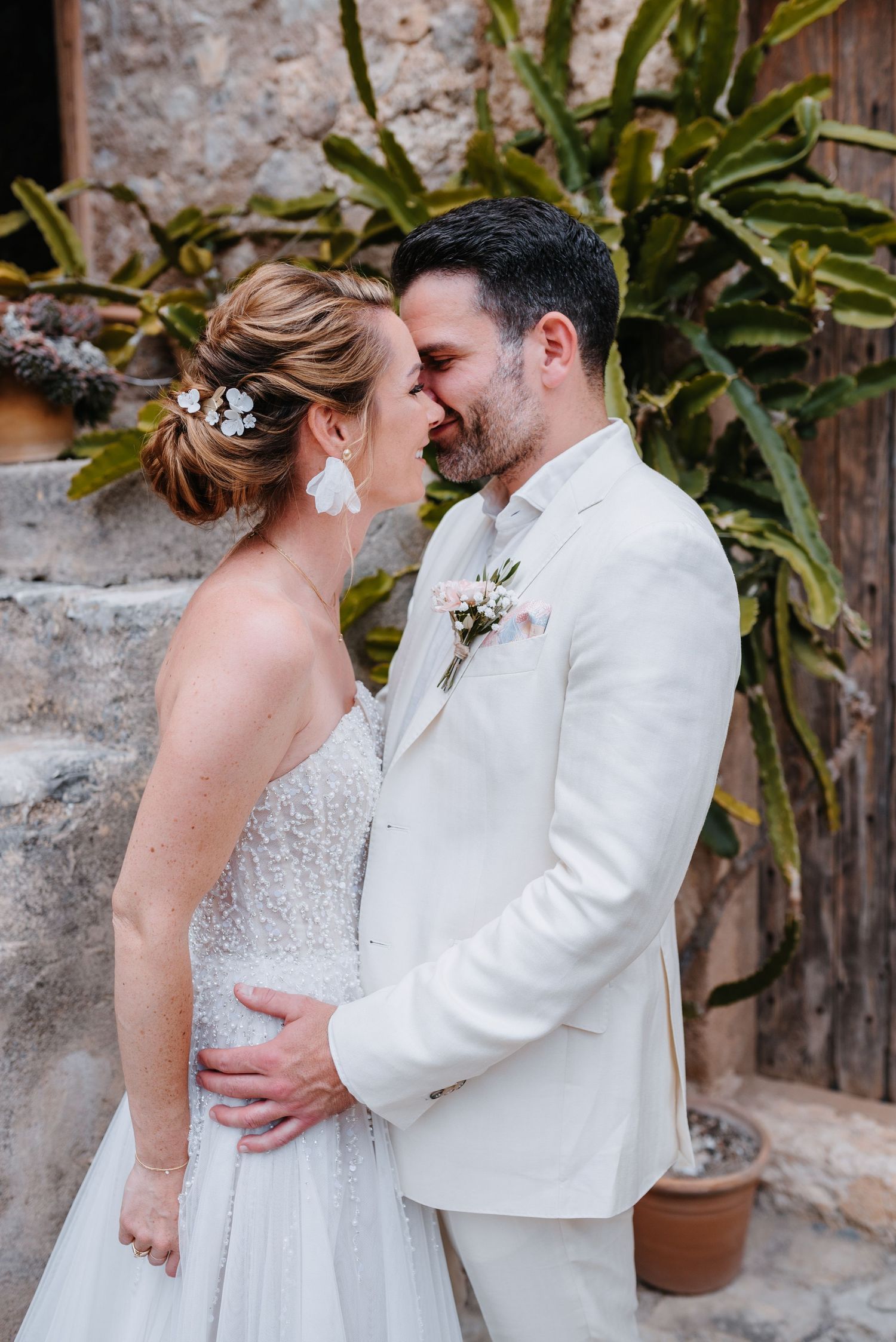 Ein romantischer Hochzeitsmoment, eingefangen zwischen einer Braut in Weiß und einem Bräutigam in einem cremefarbenen Anzug an einer Treppe.