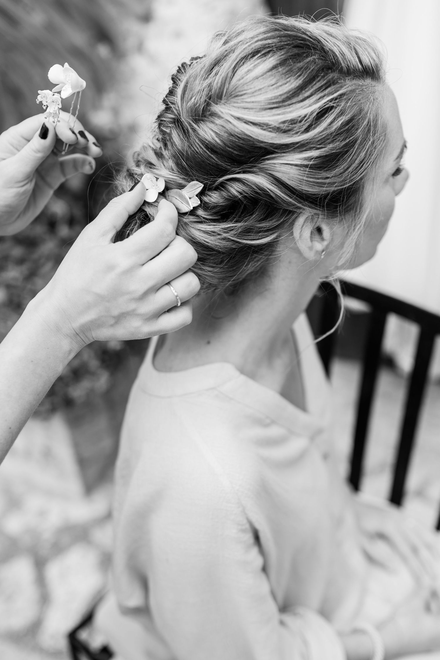 Schwarz-Weiß-Bild, das zeigt, wie die Stylistin beim Getting Ready den Haarschmuck in die elegante Brautfrisur steckt. In der Finca Xiclati.