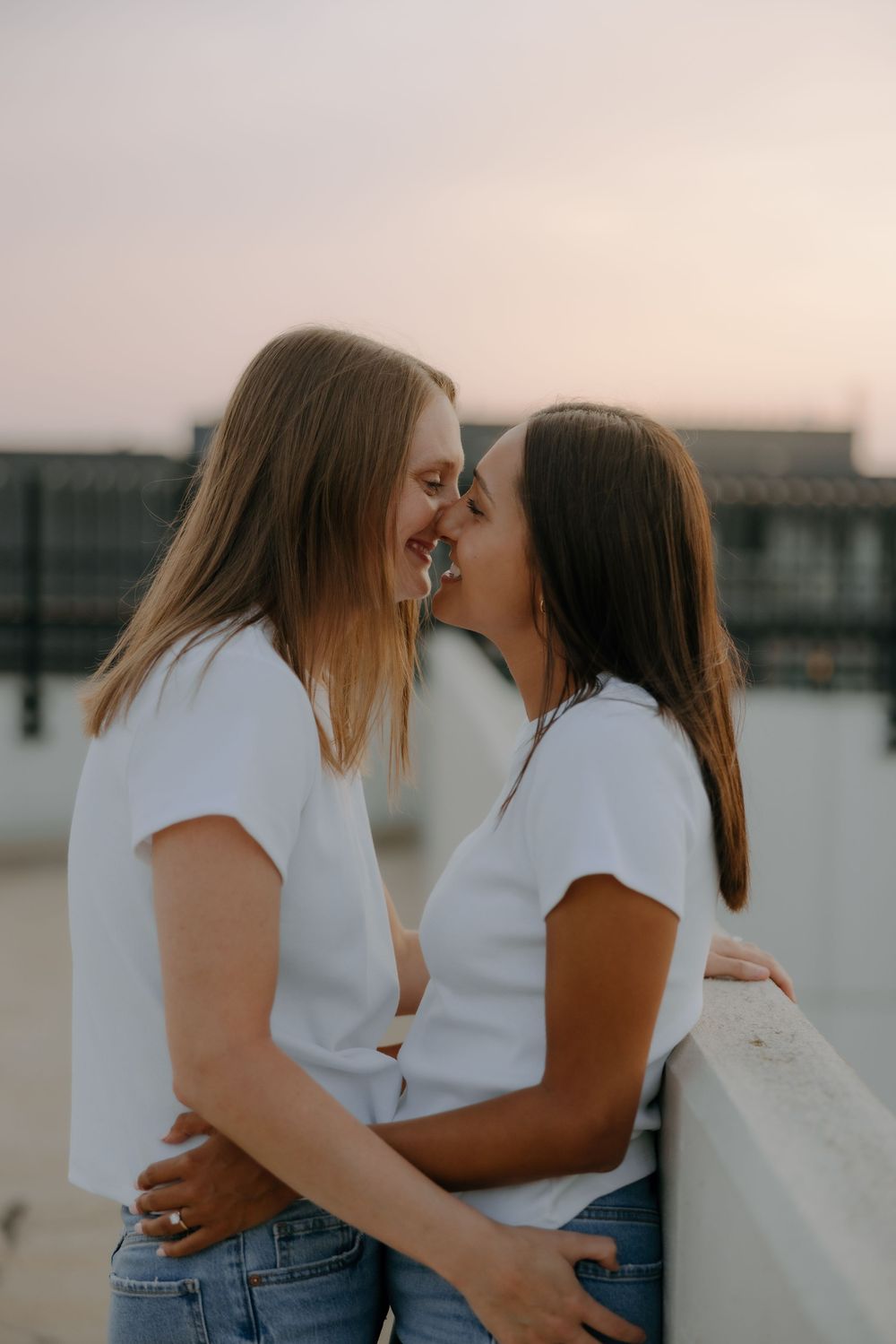 Engaged LGBTQ+ couple smiling during downtown photo session by Grand Rapids wedding photographer.