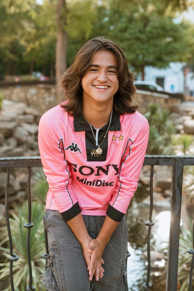 Person wearing pink Juventus MiniDisc jersey with Sony branding poses by railing in outdoor setting.