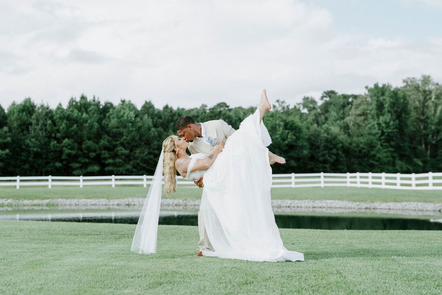 Creative wedding photography pose with flowing white dress on scenic venue grounds.