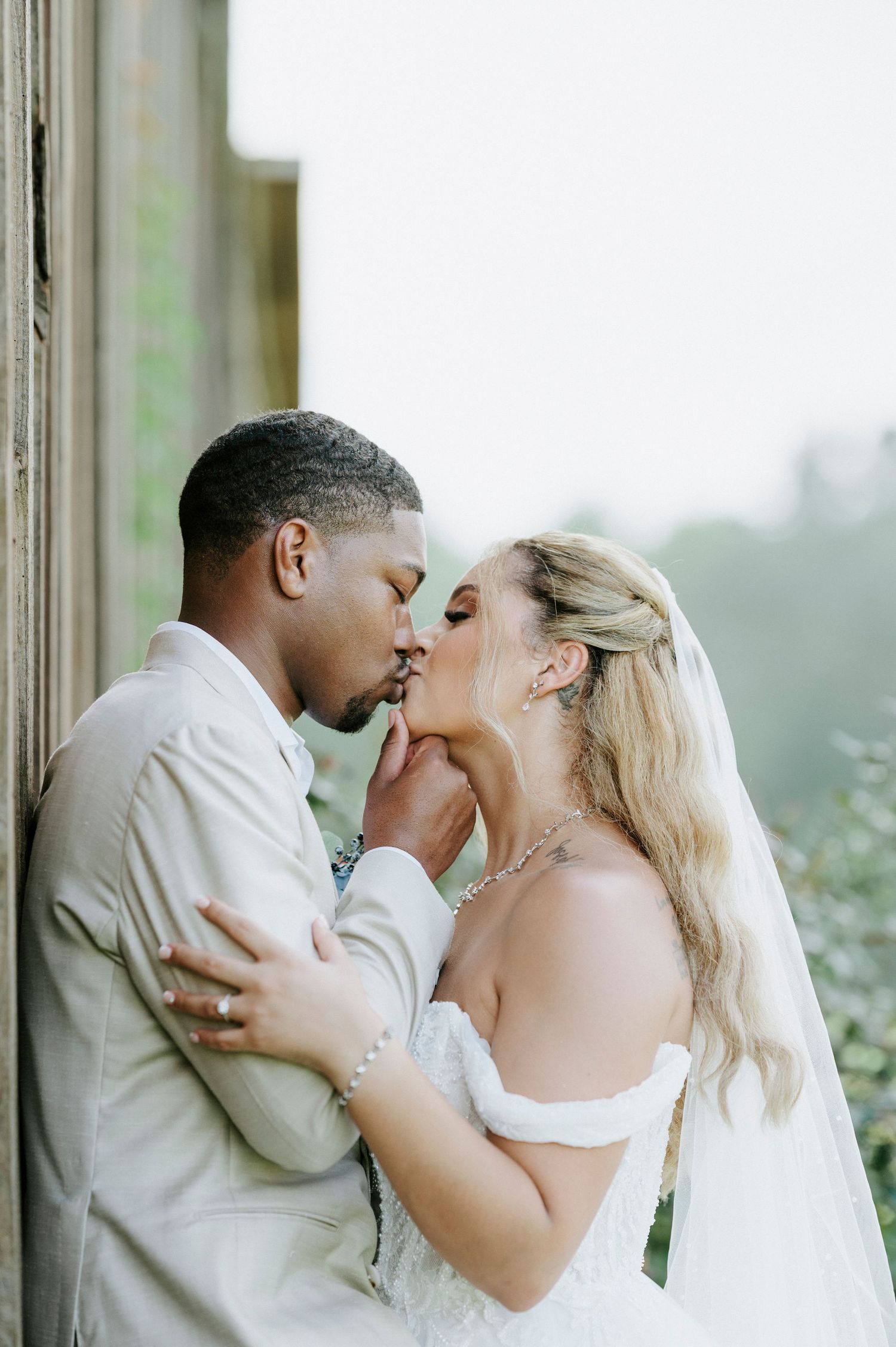 Romantic wedding couple sharing their first kiss under a wooden pergola.