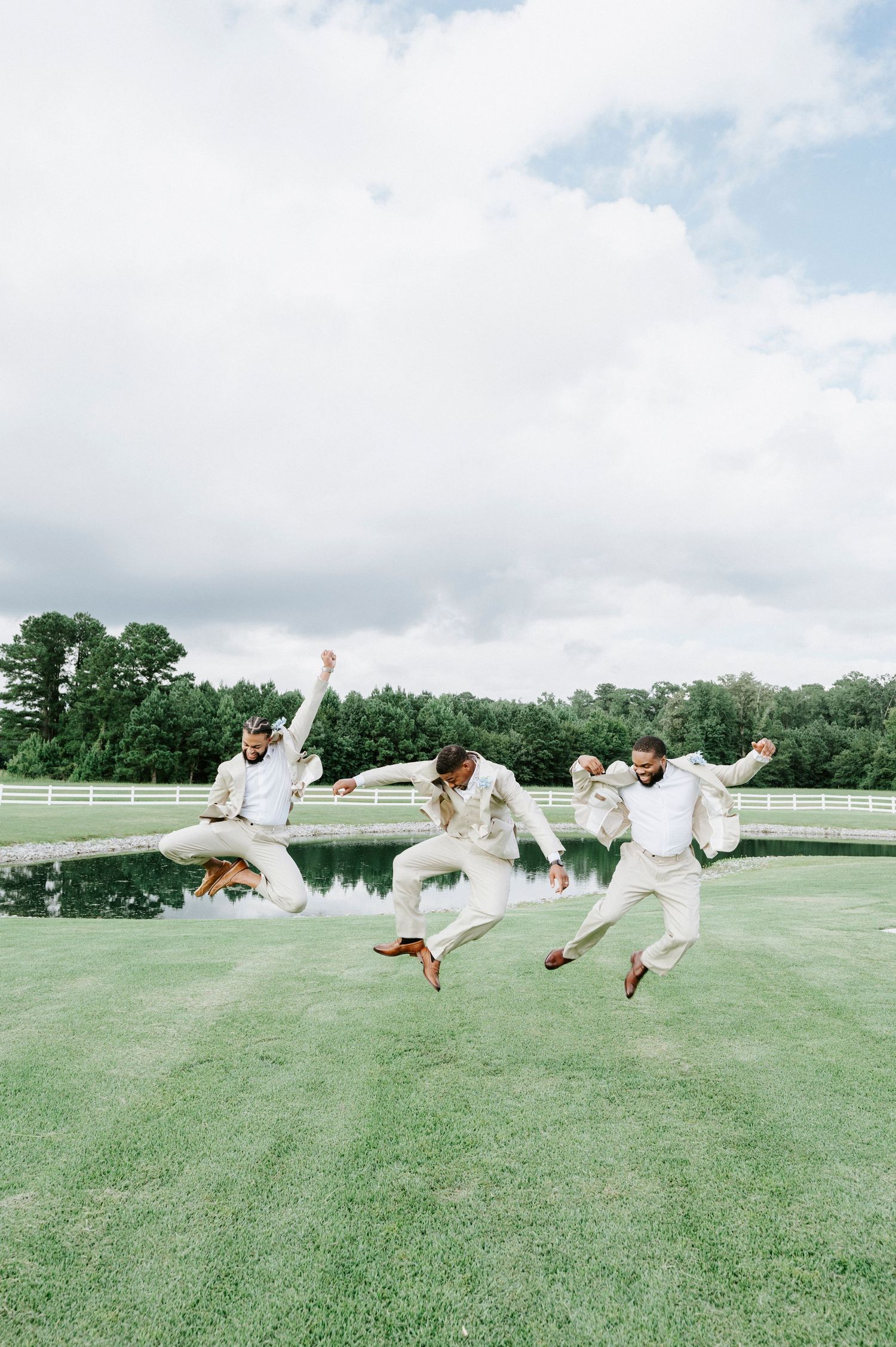 A series of people in white clothing jumping and leaping across a green grassy field with trees in the background.