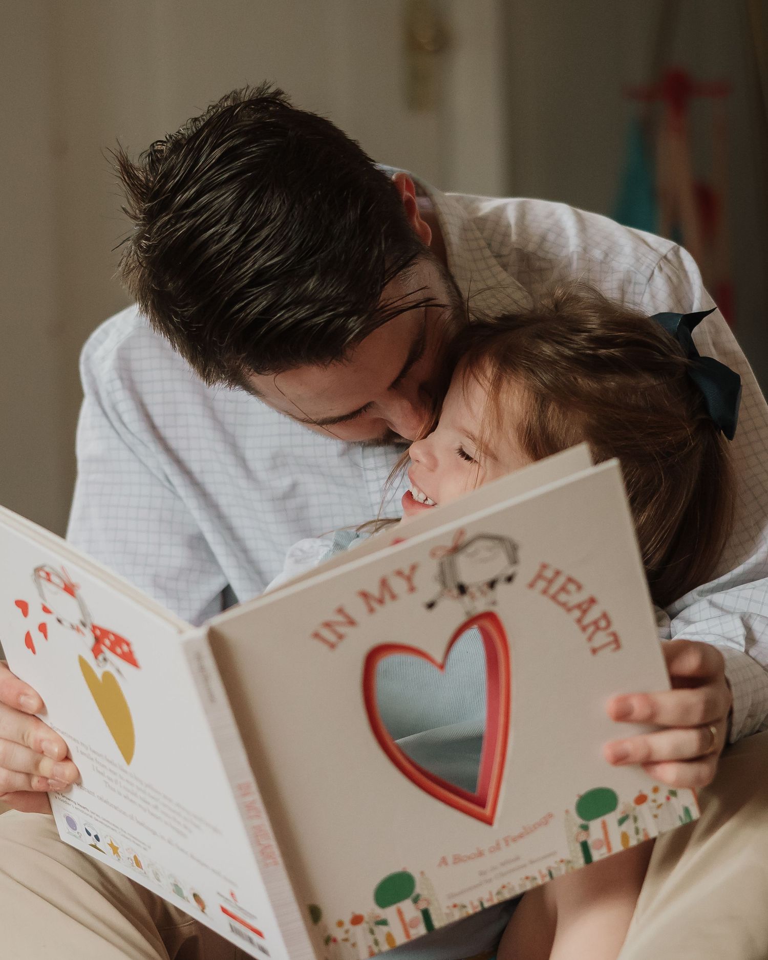 A couple affectionately sharing a moment while sitting together reading a book with heart drawings.