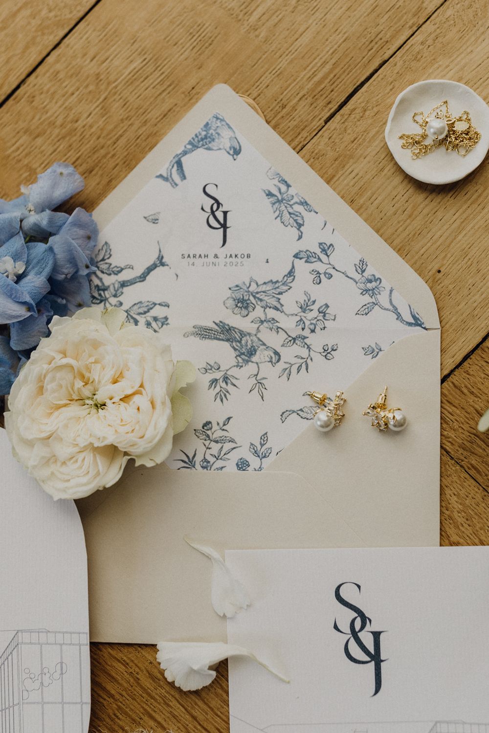 Papeterie-Flatlay einer Hochzeit in der Pfalz, der Briefumschlag hat ein blaues Inlay und ist mit weiteren Blumen dekoriert.