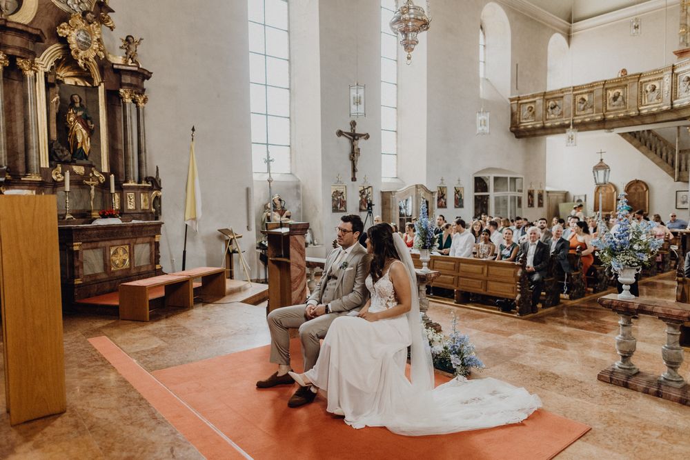 Kirchliche Trauung in der Pfalz, das Paar sitzt vorne am Altar, im Hintergrund sieht man die Gesellschaft.