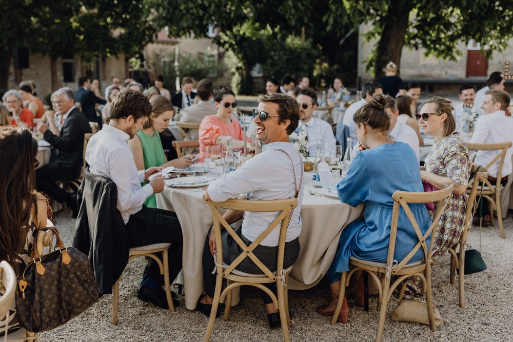 Abends bei einer Hochzeit, die Gäste sitzen an runden Tischen, die Stimmung ist gut, ein Gast dreht sich um und lacht.
