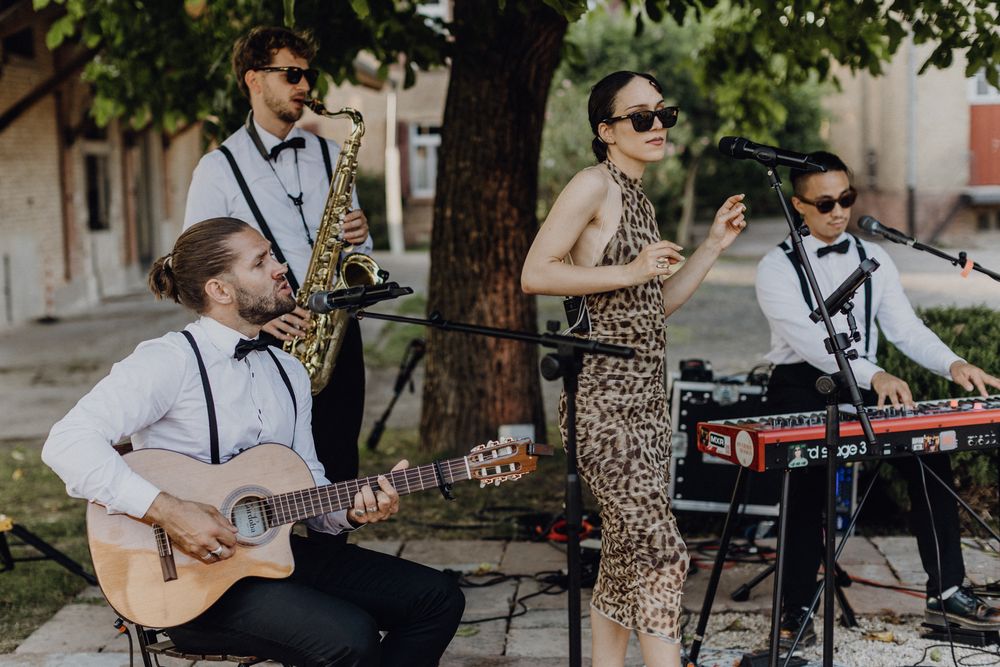Live-Band am Hochzeitstag, drei Männer und eine Sängerin. Die Männer spielen jeweils verschiedene Instrumente.